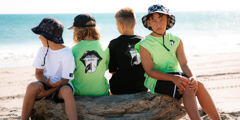 Kids sitting on a piece of driftwood at the beach 