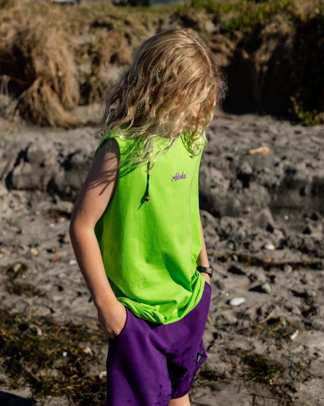 Boy wearing a lime singlet and purple shorts at the beach